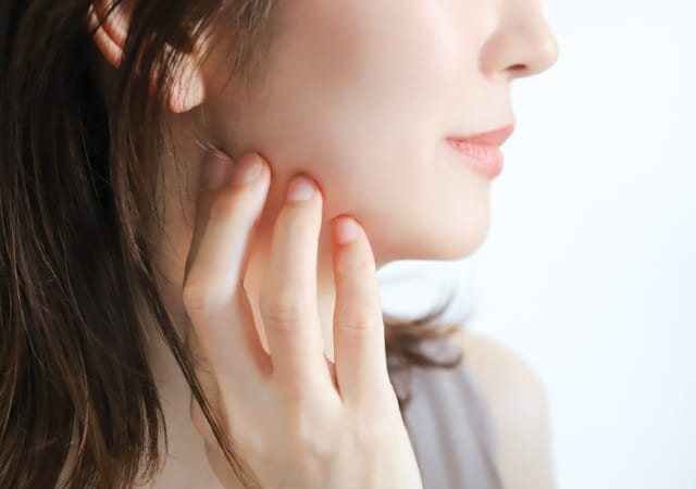女性の横顔。顎の辺りをさわっている様子。