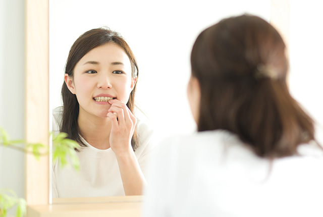 鏡で歯を見る女性